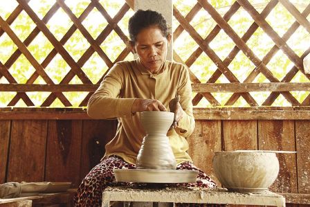 A pottery artisan is passionately creating her product.