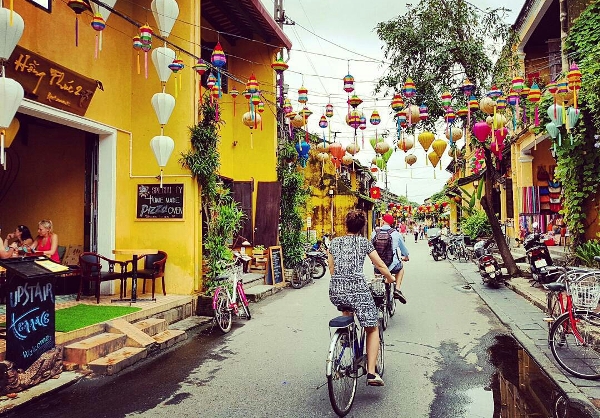 ​International tourists explore Hoi An old town by bicycle.