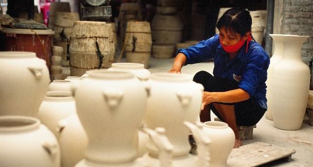 A artisan is focusing on her pottery work